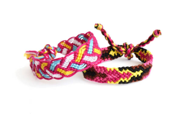 istock Selective focus of two tied woven friendship bracelets with bright pink pattern handmade of thread isolated on white background 1276354400