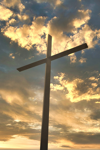 A Large Christian Cross for Jesus Christ Silhouette at Sunset