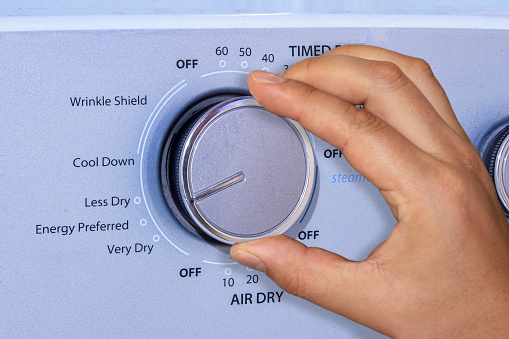A person setting up a dryer laundry machine with a high-efficiency electric dryer that reduce energy consumption.