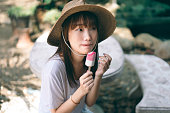 夏休みのアジアのティーンエイジャーの女性は、屋外で自宅でアイスクリームを食べてリラックス
