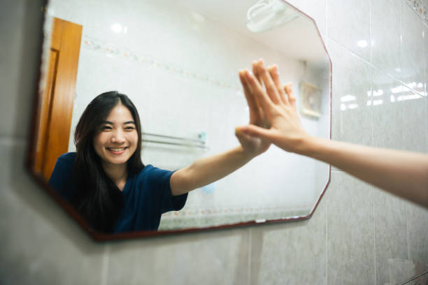 Young adult smile asian woman practice self talk conversation in the morning in bathroom at home Young adult smile asian woman practice self talk conversation in the morning in bathroom at home. Hand hi-touch at mirror. Healthy lifestyle after wake up concept. individuality stock pictures, royalty-free photos & images