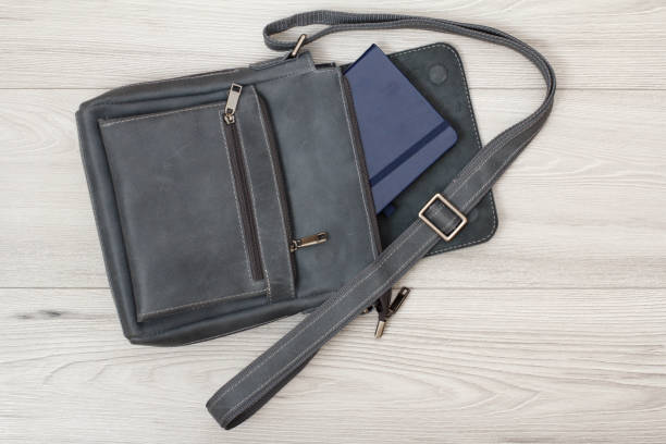 istock Leather shoulder bag for men with notebook in it with gray wooden background 1276369336