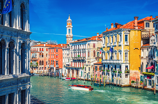 Grand Canal waterway in Venice historical city centre with yacht boat, Venetian architecture colorful buildings and Church of the Holy Apostles of Christ bell tower. Veneto Region, Northern Italy.