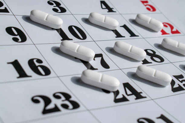 Close up of white pills on a calendar. Medication plan, schedule, list or calendar concept. stock photo