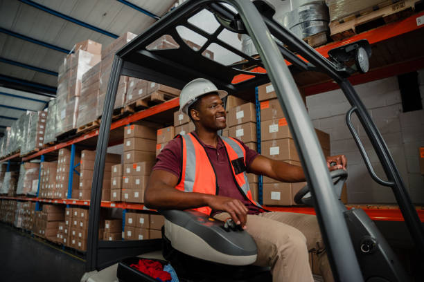 istock Mixed race worker driving forklift around warehouse while searching for parcels 1276379299