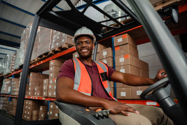 istock Smiling ethnic worker sitting in forklift locating parcels for delivery 1276379401