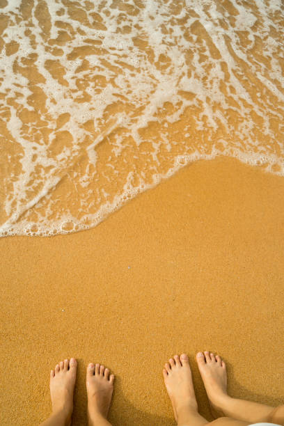 istock Feet stand on sea sand and wave with space 1276380994