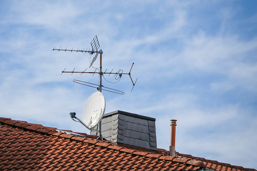 Satellite dish and terrestrial antenna on the roof against the sky