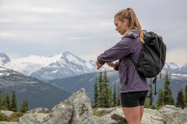 la excursionista femenina comprueba el tiempo y las funciones vitales junto al sendero - fresh snow audio fotografías e imágenes de stock