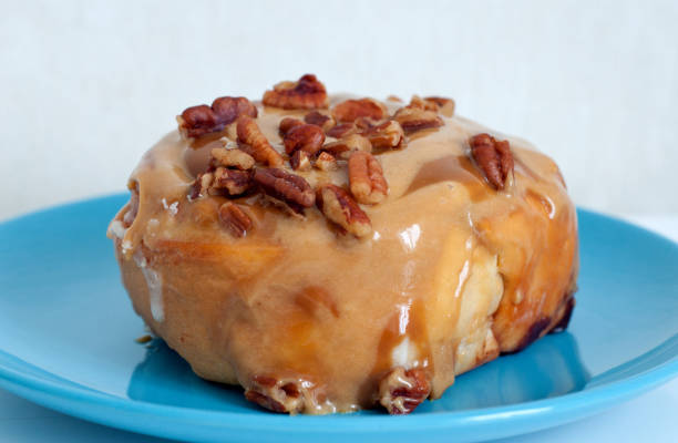 istock A sweet cinnamon bun topped with caramel and pecans. Dessert on a blue plate. 1276391877
