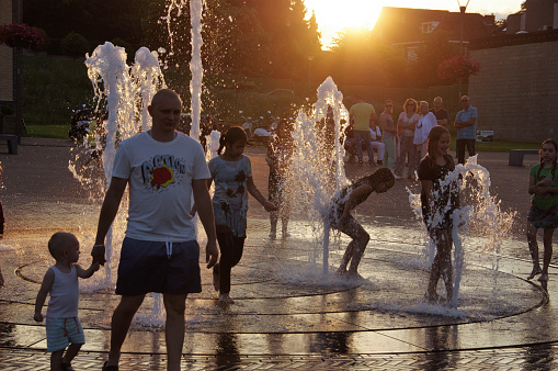 Brunssum, the Netherlands, - July 18, 20186. People with there children playing in the city fountain on a warm summer evening.