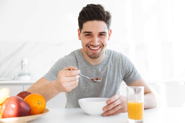 istock Happy brunette man sitting by the table and eating 1276394997