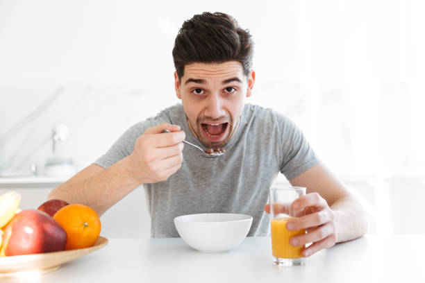 istock Young brunette man sitting by the table and eating 1276395309