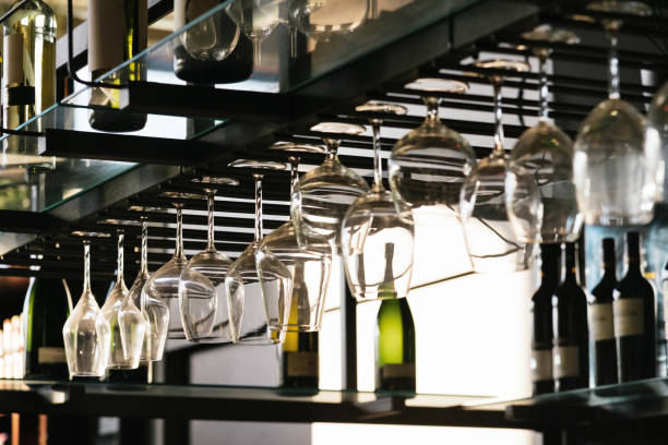 Wine bar shelf with glasses hanging Wine bar shelf with glasses hanging by day. Dark and moody detail of wine bar. wine bar counter stock pictures, royalty-free photos & images