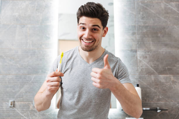istock Cheerful brunette man brushing his teeth in bathroom 1276397301