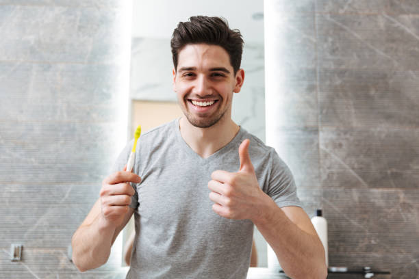 istock Happy brunette man brushing his teeth in bathroom 1276398150
