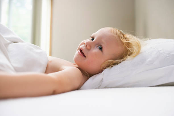istock Young girl (1-2) lying in bed smiling 1276400434