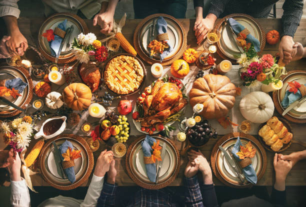 Thanksgiving celebration traditional dinner concept Group of friends or family members giving thanks to God at festive turkey dinner table together. Thanksgiving celebration traditional dinner concept banquet stock pictures, royalty-free photos & images