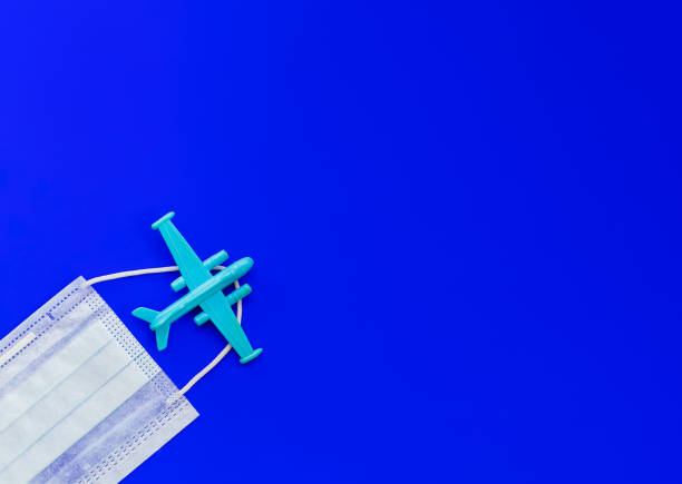 istock Airplane and medical face mask on a blue background. Flat lay, copy space, top view. Summer concept, pandemic, coronavirus. 1276404487