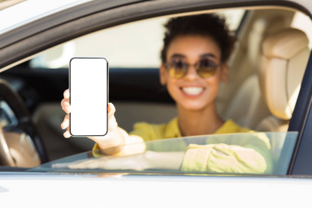 istock Smiling Woman Showing Phone With Empty Screen Sitting In Auto 1276408229