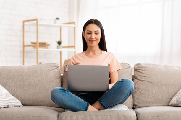 istock Woman using laptop phone sitting on sofa, free space 1276412640