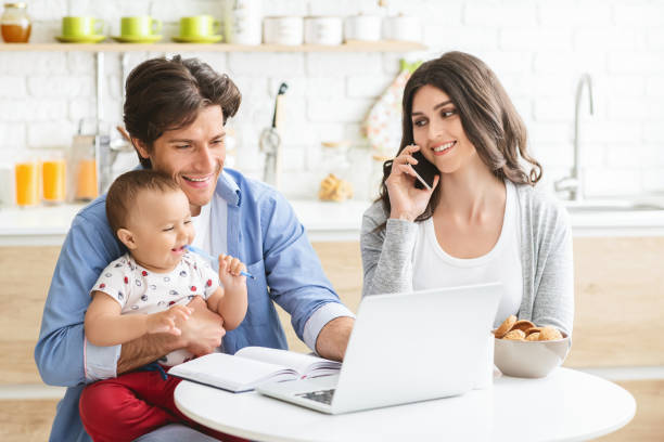 istock Millennial parents with baby son working on laptop at kitchen 1276412953
