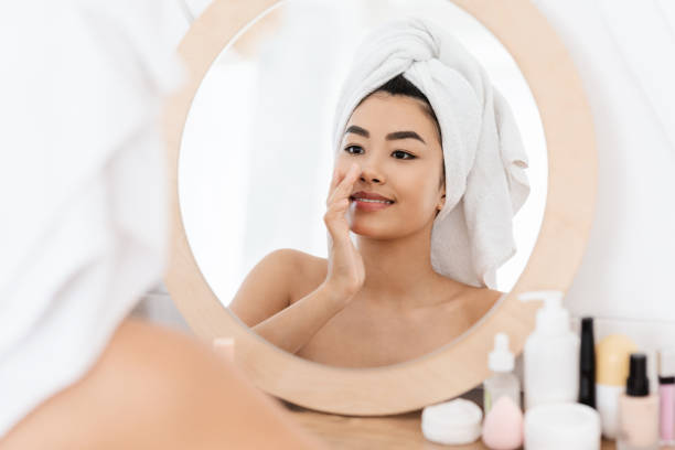 istock Attractive asian young woman applying face cream 1276413140