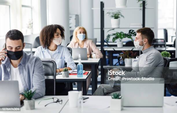 Meeting Of Colleagues In Coworking Office During Coronavirus Epidemic Multiracial Workers Of Modern Company In Protective Masks Discussing Work Issues Stock Photo - Download Image Now