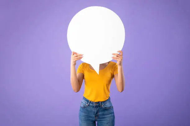 Photo of Portrait of woman hiding face behind speech bubble