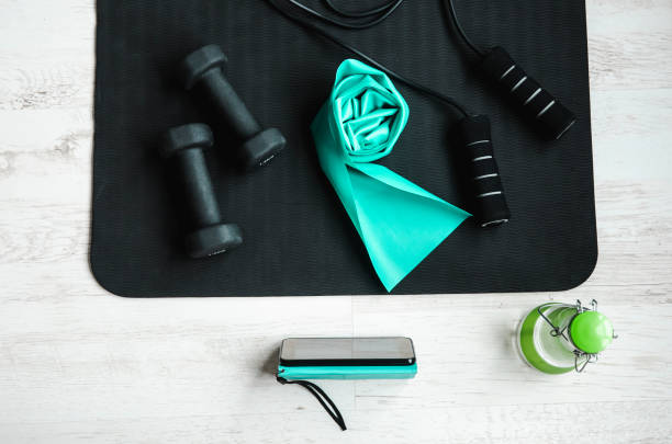 istock Online training class concept. Video from smartphone screen. Top view of home workout equipment, jumping rope, resistance exercise latex rubber band, dumbbells. 1276415834