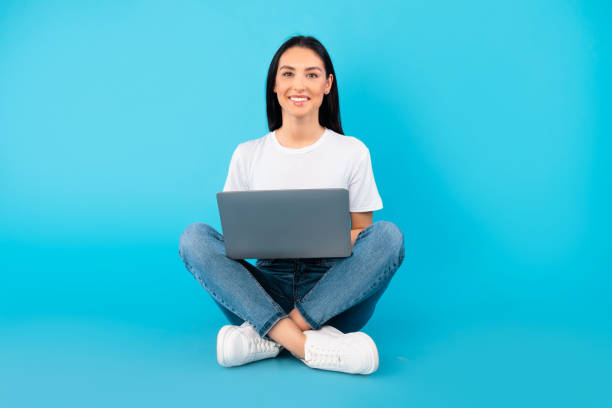 istock Happy smiling lady sitting with laptop on the floor 1276417863