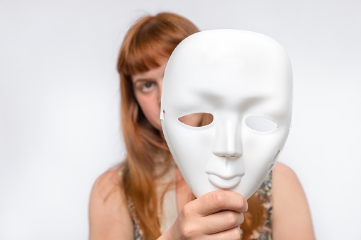 Mysterious woman cover her face behind a white mask