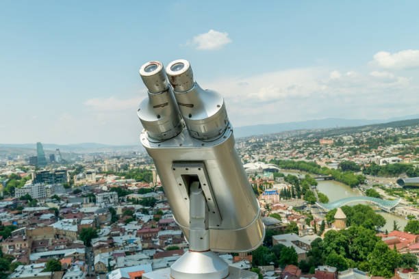 los binoculares de cerca con vistas a tiflis, la capital georgiana en el fondo en un día soleado. dispositivo gris para hacer turismo, visualización estacionaria de prismáticos, ver prismáticos con aceptador de facturas. - binoculars watching optical instrument closed fotografías e imágenes de stock