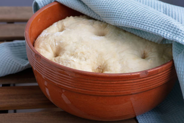leavened dough in ceramic bowl on wooden table