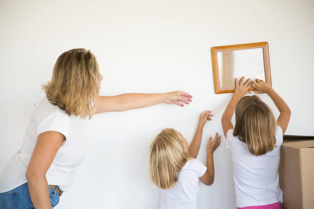 istock Little girl putting photo frame on white wall 1276421910