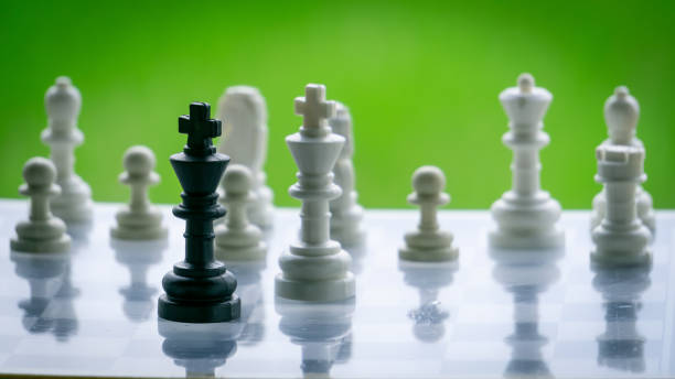 istock Wooden chess pieces in board game with green background 1276422093