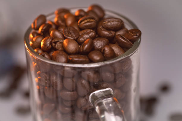 freshly brewed coffee bean placed on a transparent glass cup with yellow smoky tint on top of the seeds