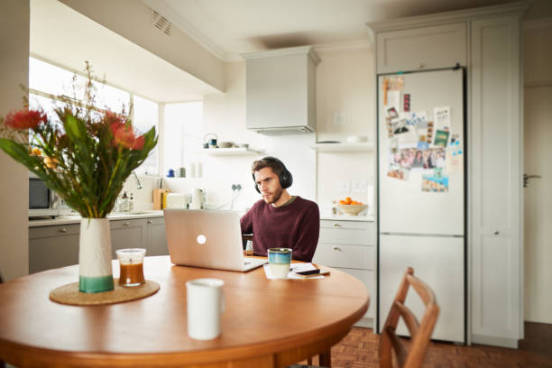 istock Young man working remotely in his kitchen with a laptop 1276423045