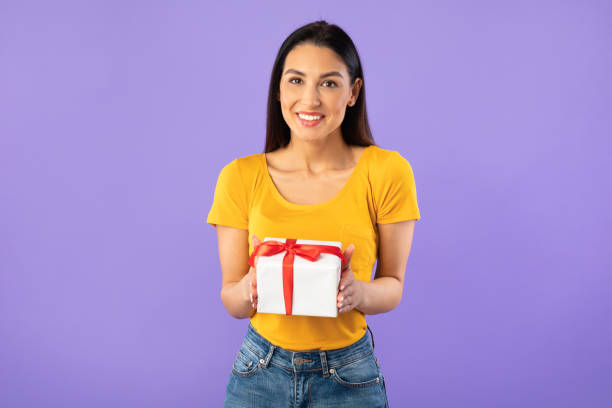 istock Happy woman holding gift box at studio 1276424162