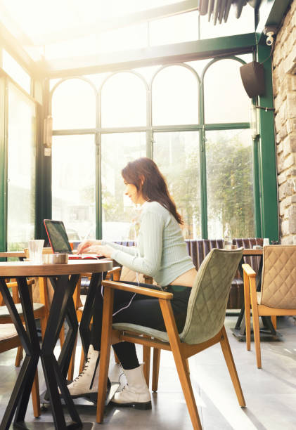 istock Young Woman Drinking Coffee and Using Laptop in a Cafe 1276426921