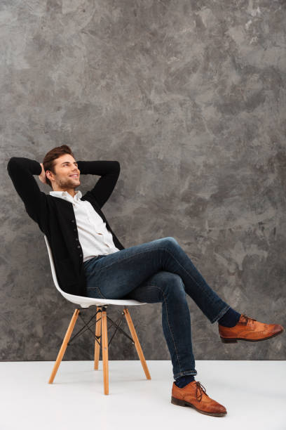 istock Cheerful young businessman sitting over grey wall 1276431251