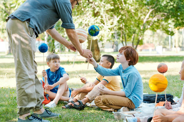 istock Teacher giving planet models to pupils 1276431676