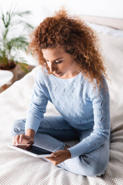 istock Curly woman using digital tablet with blank screen on bed 1276432279