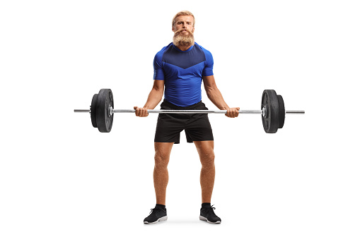 Full length portrait of a strong young man with beard and moustache lifting weights isolated on white background