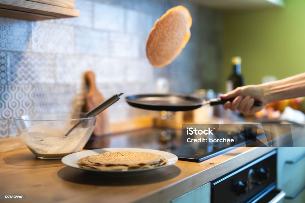 Making Pancakes Close-up of man's hand tossing pancakes on pan in the kitchen. Pancake Stock Photo