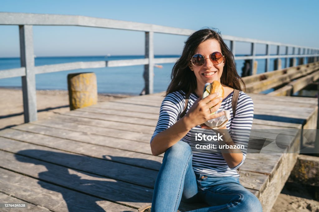 Fish sandwich at Travemünde Young cute caucasian woman eating sandwich with salted fish at Travemünde. Fish Stock Photo