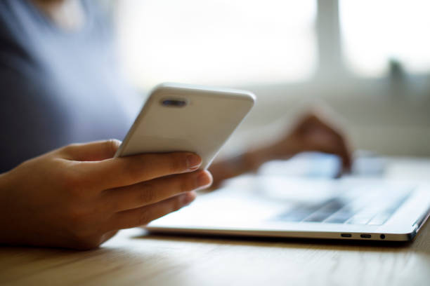 istock Woman using mobile phone and laptop for working 1276435309