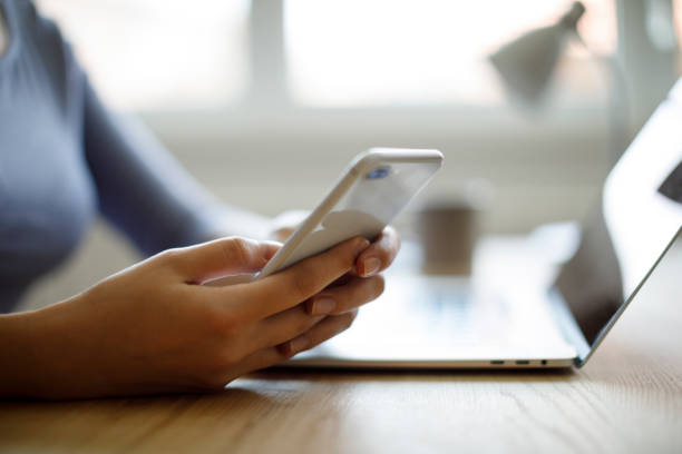 istock Woman using mobile phone and laptop for working 1276435429