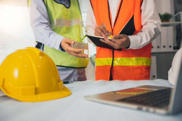istock close up helmet of engineer explaining project work on laptop and discussing about drawing blueprint as partner writing data on paper, architect meeting, brainstorming of designer and teamwork concept 1276436946