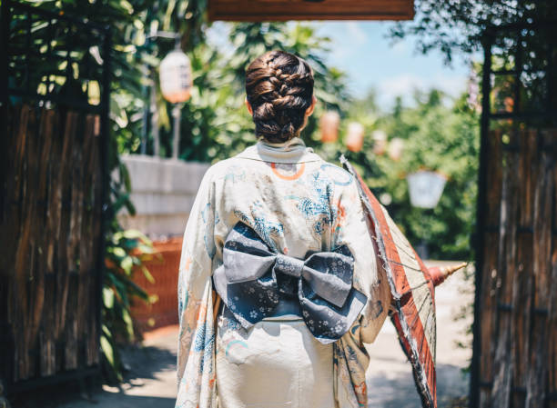 Rear view of Japanese woman wearing Yukata dress while walking in town. A Japanese yukata is a lightweight form of kimono, which is worn casually during the summer. yukata photos stock pictures, royalty-free photos & images